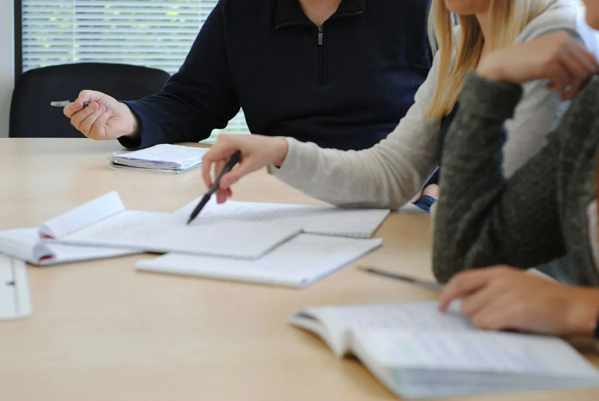 Persone sedute a un tavolo prendono appunti durante un incontro di lavoro