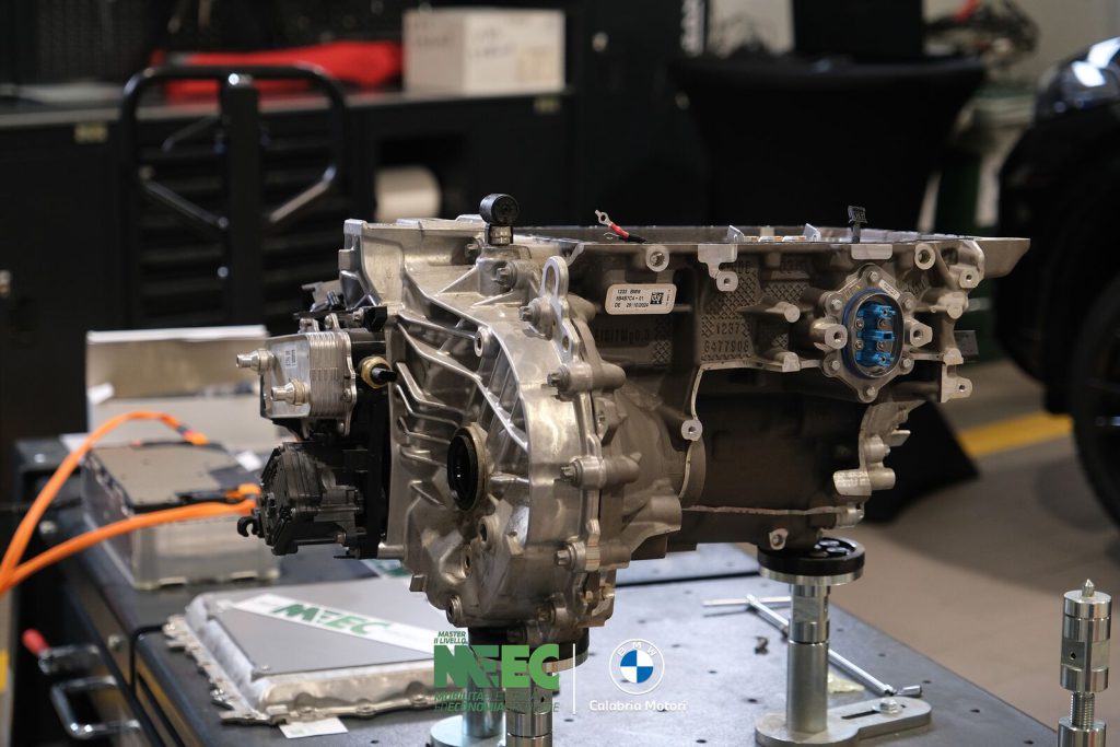 Motore elettrico con cablaggi ad alta tensione arancioni montato su banco didattico in officina