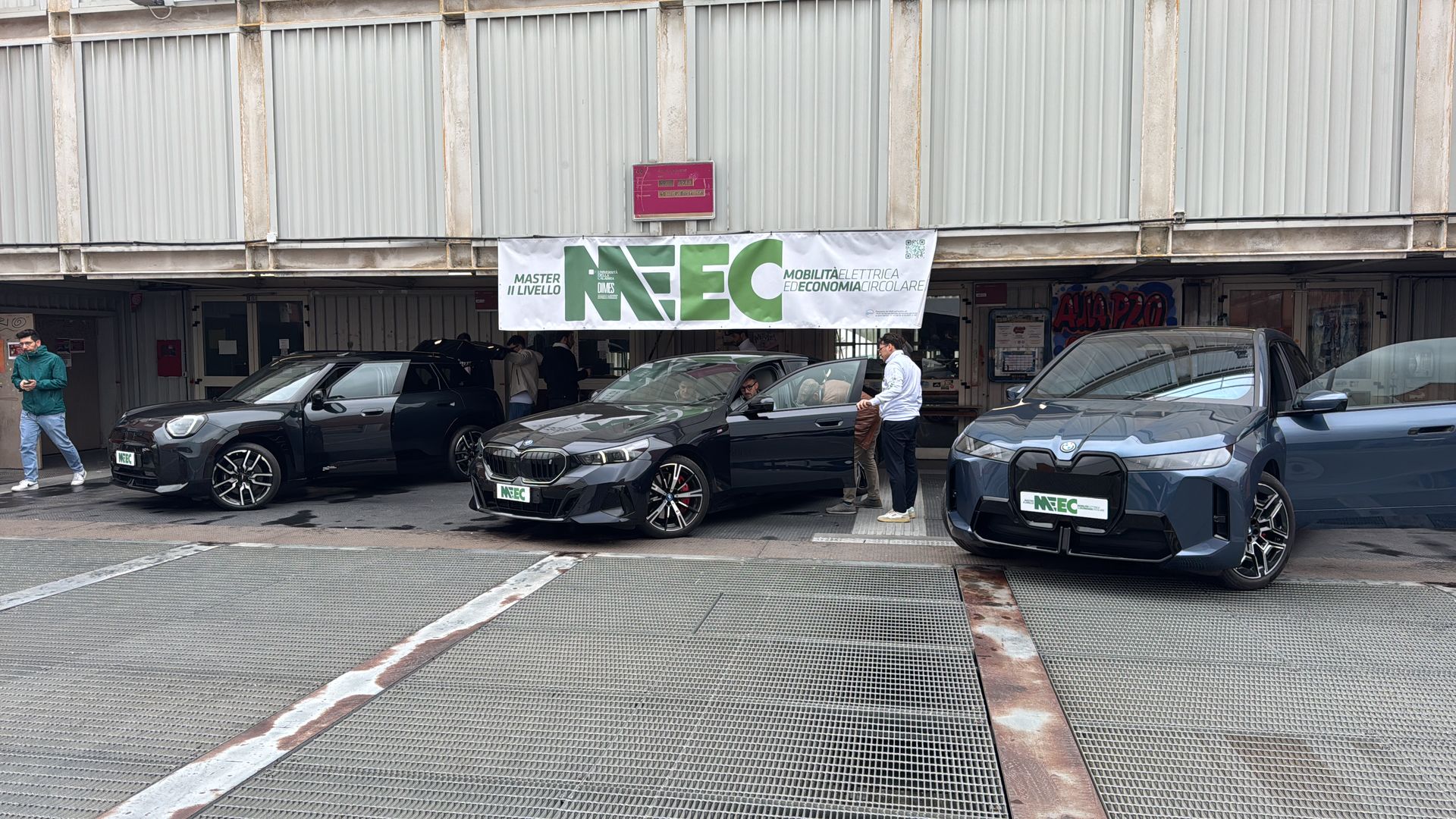 Auto elettriche schierate davanti allo striscione MEEC per le prove su strada del modulo powertrain